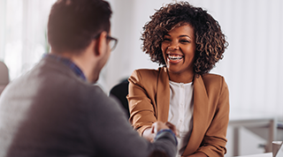 A Black middle-aged customer smiles as she meets with a TD colleague. 