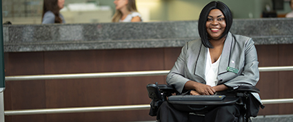 A male TD colleague greets a female customer that uses a  motorized wheelchair at a TD branch.