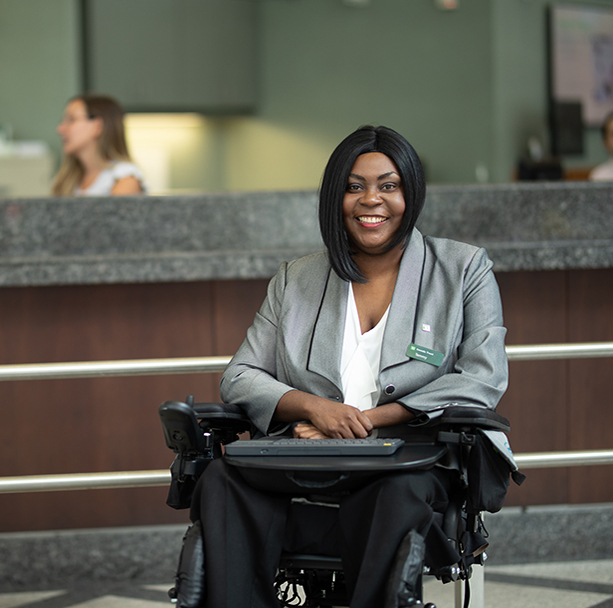 Man in wheelchair sitting with woman looking at laptop