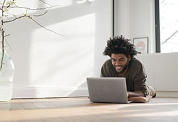 Smiling-young-man-on-floor-with-laptop