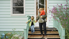 Une mère qui descend les marches de sa maison avec ses deux enfants