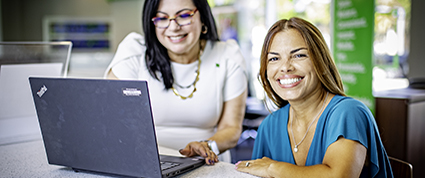 Une collègue de la TD portant un hijab travaille dans un bureau contenant deux fauteuils verts et une tasse à café verte.