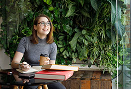 Jeune-femme-souriante-avec-un-café-et-des-livres
