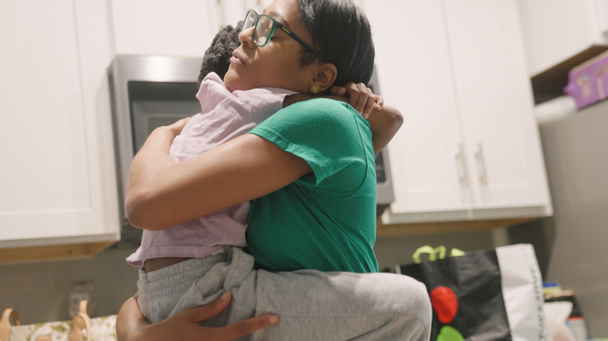 Child and adult hugging in a kitchen