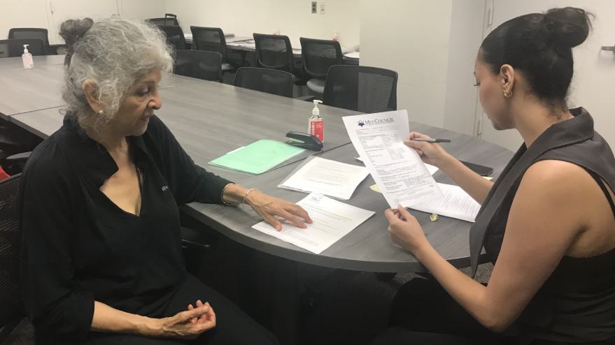 Two women sitting at a table and looking at paperwork